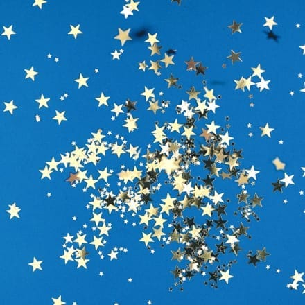 Gold confetti in the shape of stars against a blue background.