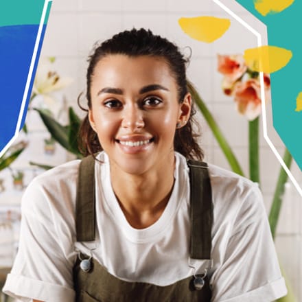 A smiling young woman in front of flowers.