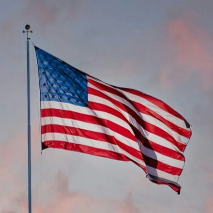 The American flag flying on a flag pole.