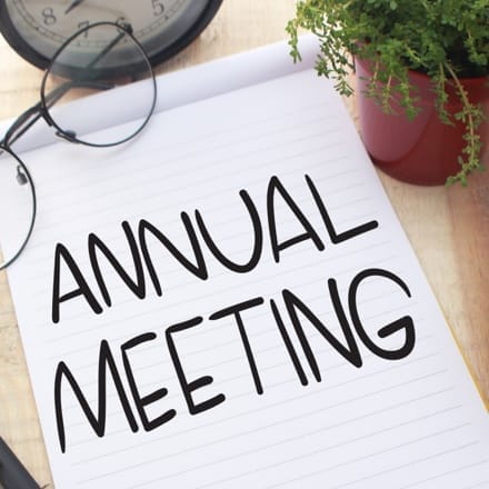 An open notebook with the words written at the center: annual meeting