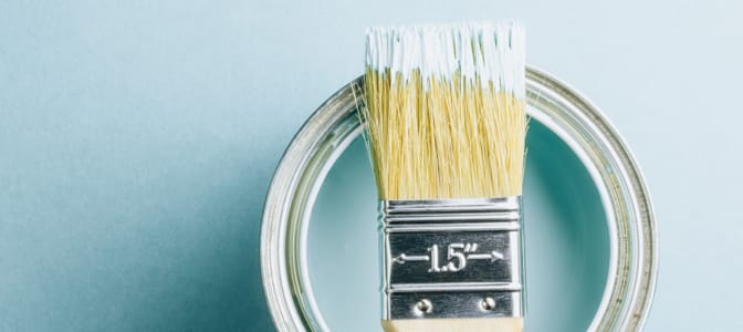 A paintbrush on top of a paint can.