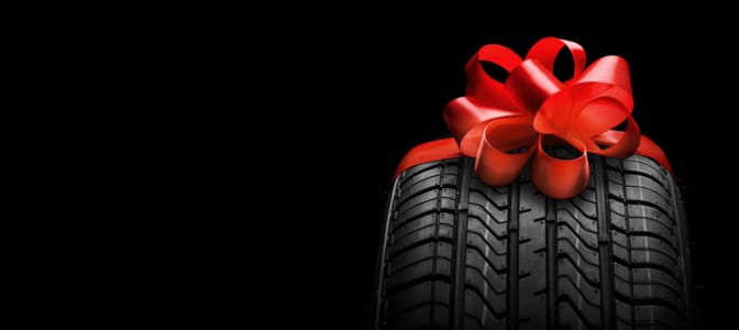 A tire wrapped in a red bow.
