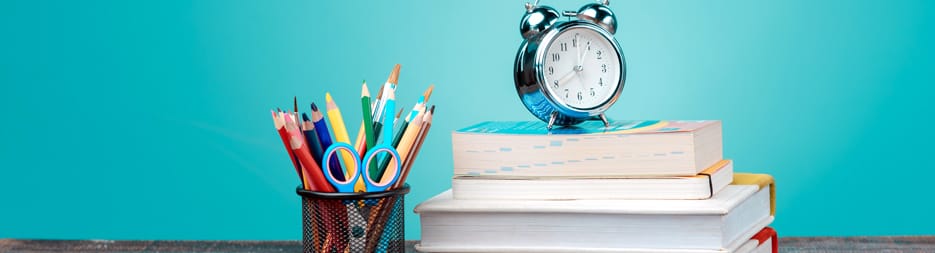 A silver alarm clock resting on a stack of books.
