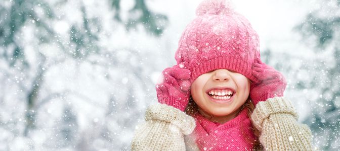 A young professional smiling down at a laptop while holding a credit card.