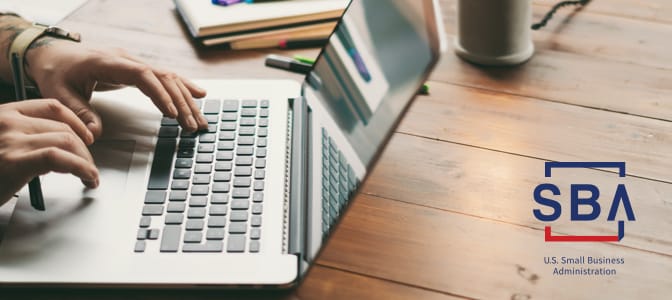 A person sitting at a desk using a laptop. At the bottom right, the SBA logo.