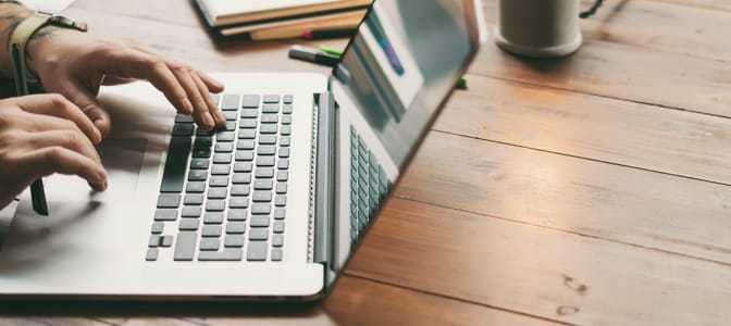 A person sitting at a desk using a laptop.