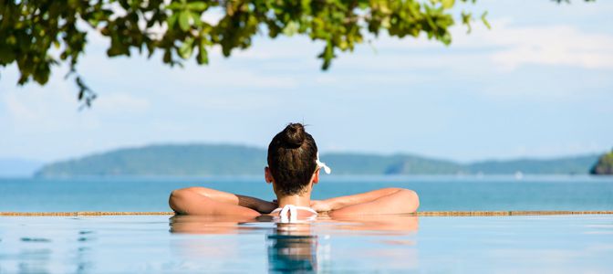 A couple sitting on a deck overlooking a beautiful overwater bungalow.