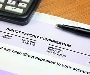 A calculator and pen on top of a Direct Deposit Confirmation document